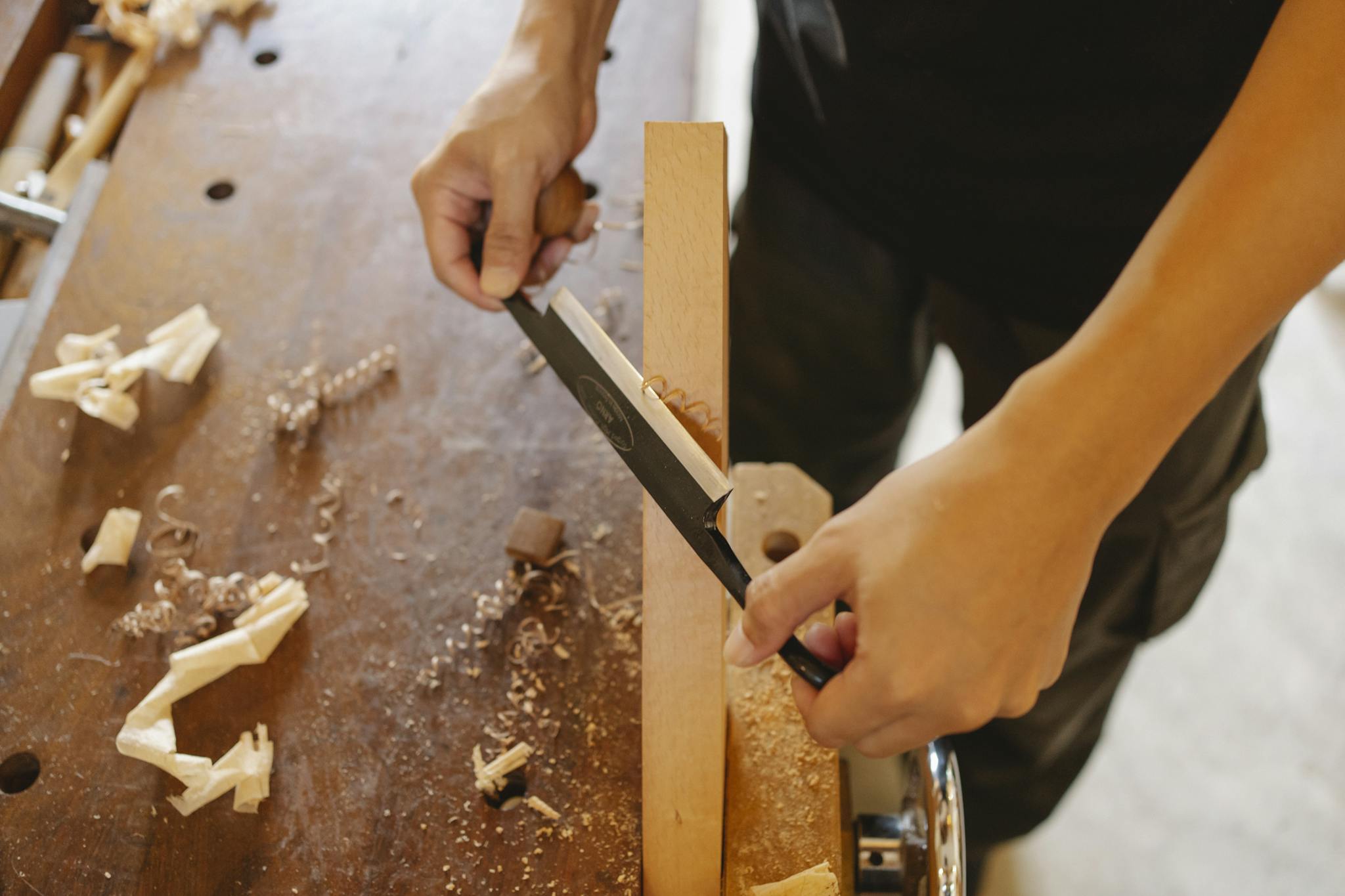 Woodworker cutting wood with knife in workshop